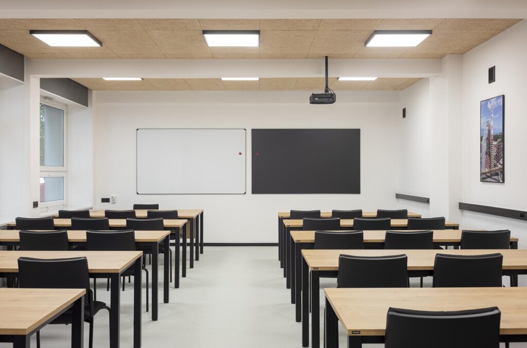 Pusta nowoczesna sala lekcyjna z rzędami biurek i krzeseł, tablicą oraz projektorem