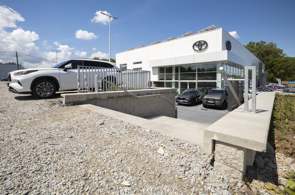 Salon Toyoty z przeszklonym budynkiem, zaparkowanymi samochodami i białym SUV-em na pierwszym planie