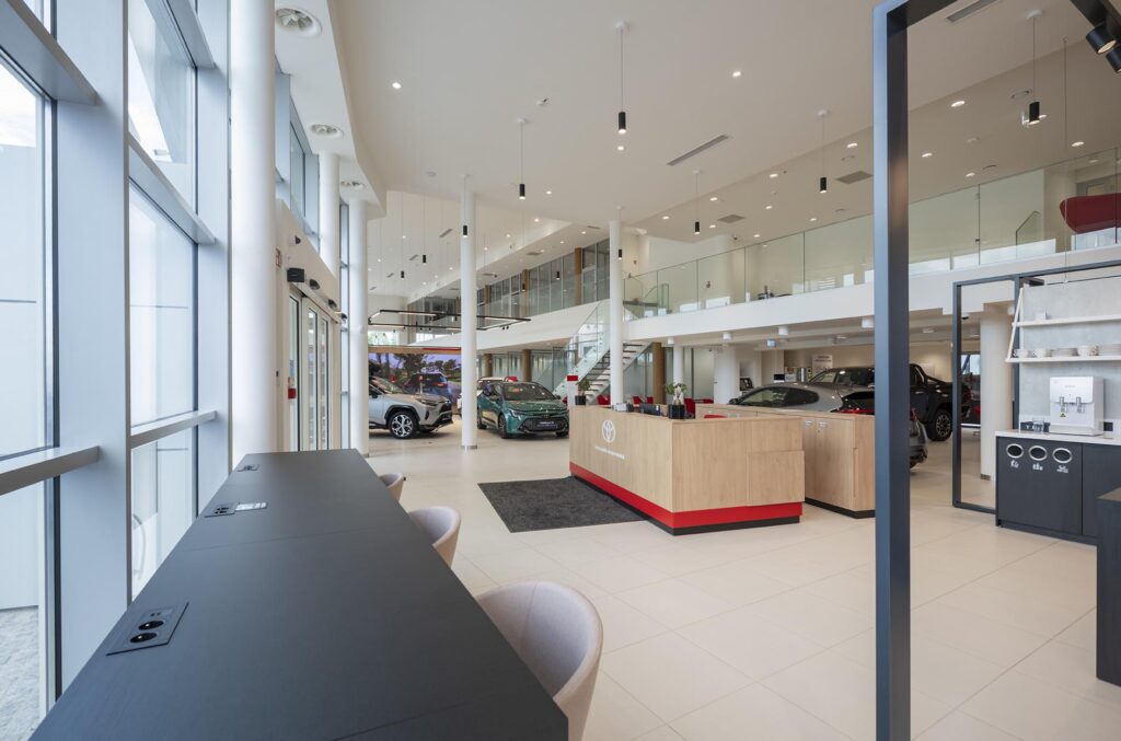 Jasne nowoczesne wnętrze salonu samochodowego z recepcją i wystawionymi autami