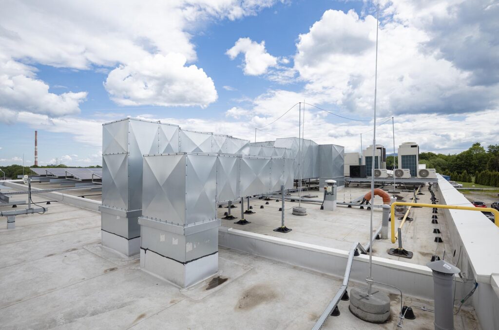 Płaski dach z metalowymi kanałami wentylacyjnymi, jednostkami klimatyzacji i instalacjami technicznymi